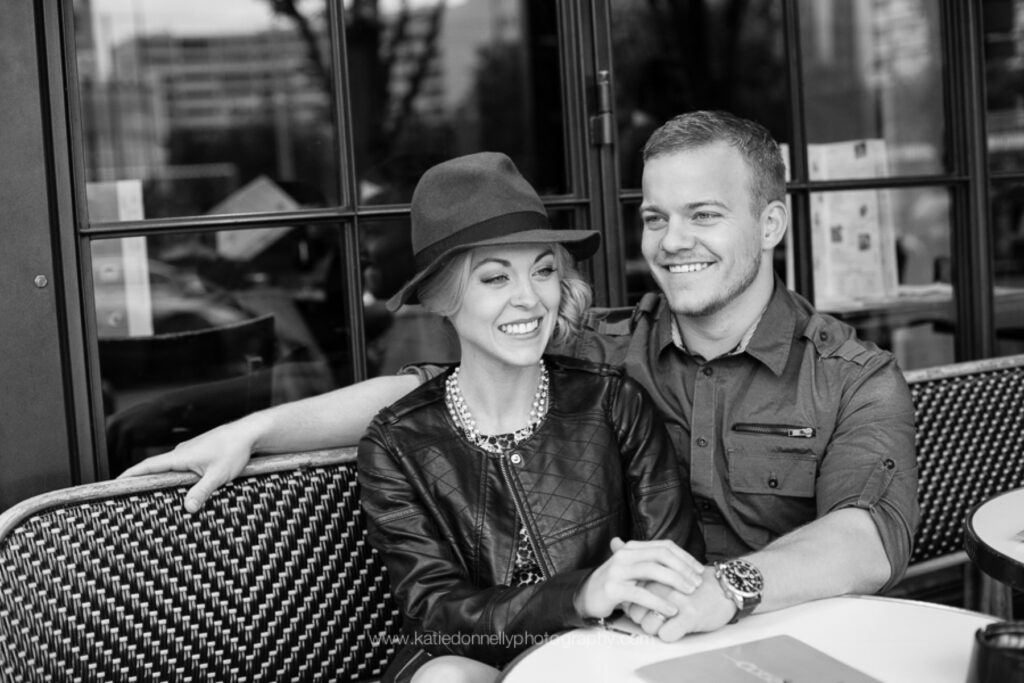 Black and white photo of a couple sitting side by side on a Paris café terrace