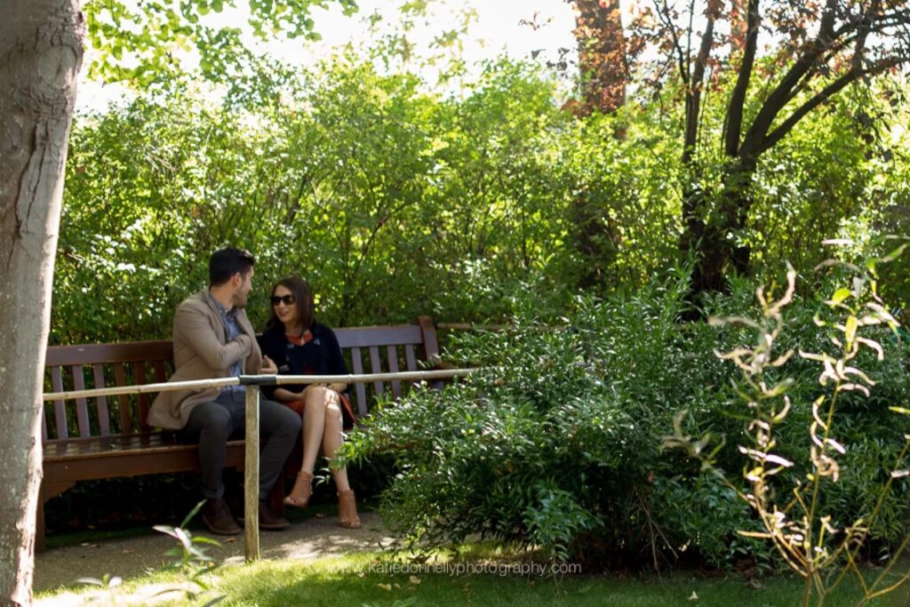 Couple sitting on a wooden bench in Monet's garden in Giverny moments before the proposal