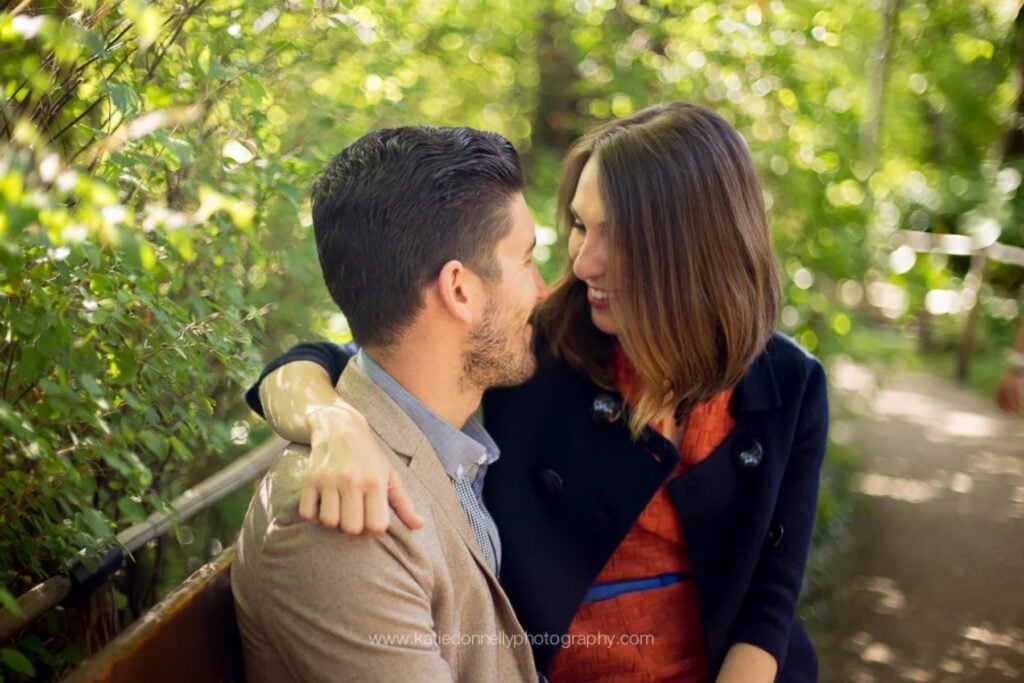 Engaged couple smiling at each other on a garden path after a Giverny proposal