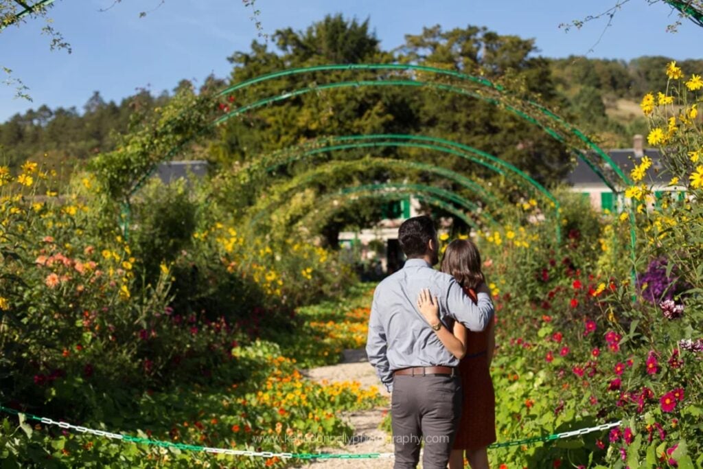 Couple walking away under the flower arches of the Grande Allée in Monet's garden, Giverny