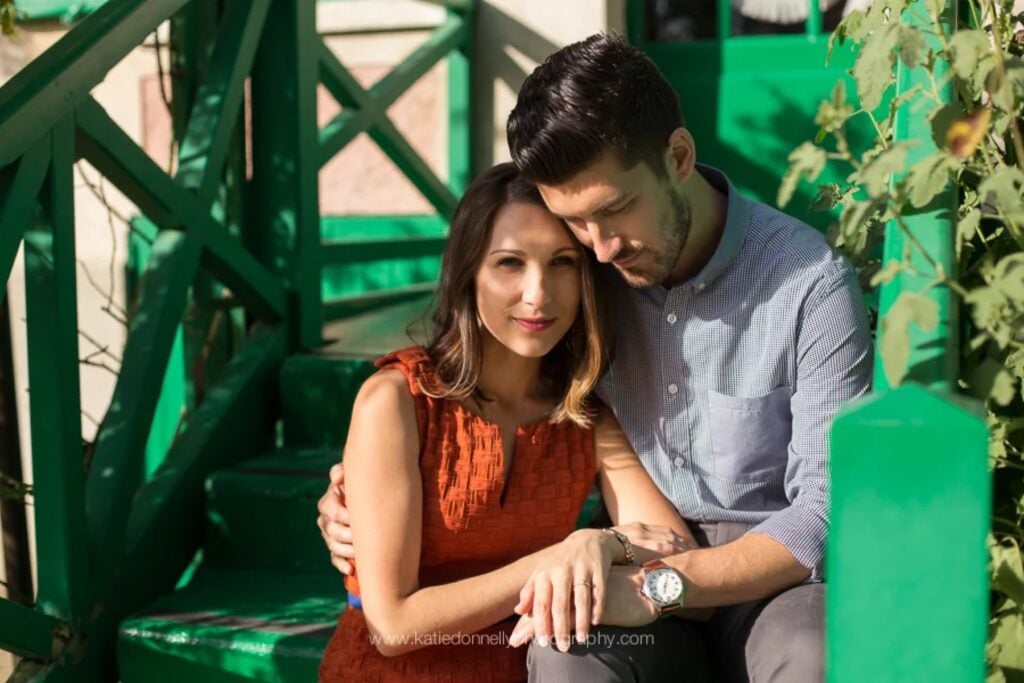 Newly engaged couple sitting on the green steps of Monet's house in Giverny