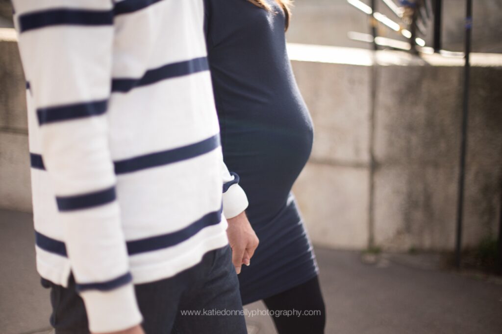 Close-up of a striped sweater and a baby bump as an expecting couple walks together