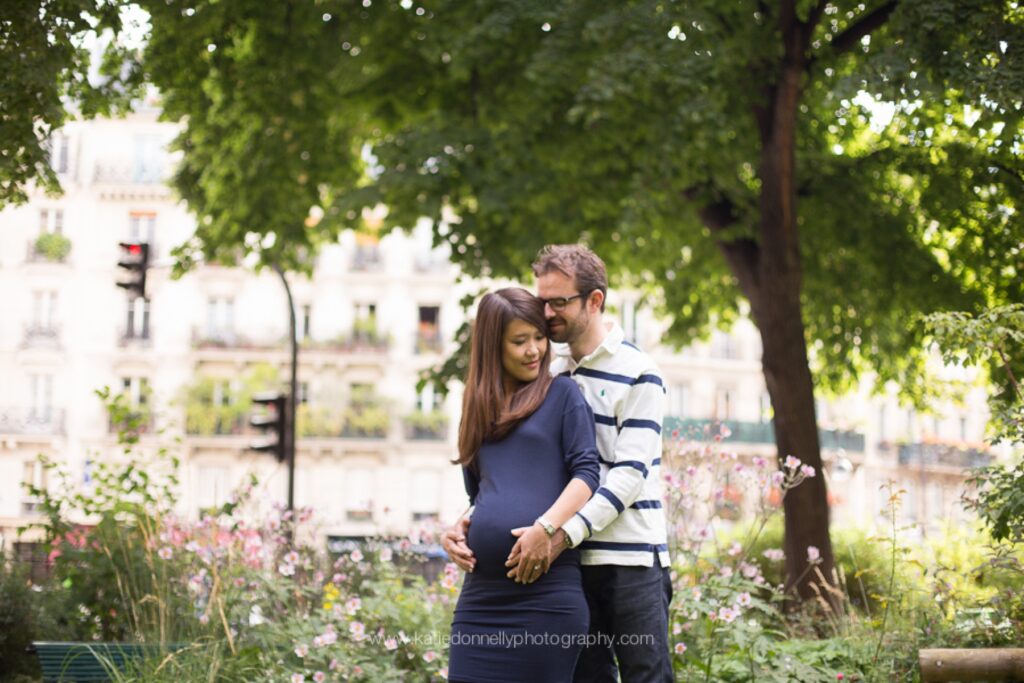Expecting couple embracing under the trees beside the Seine in Paris