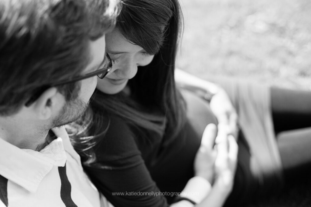 Black and white close-up of an expecting couple laughing together