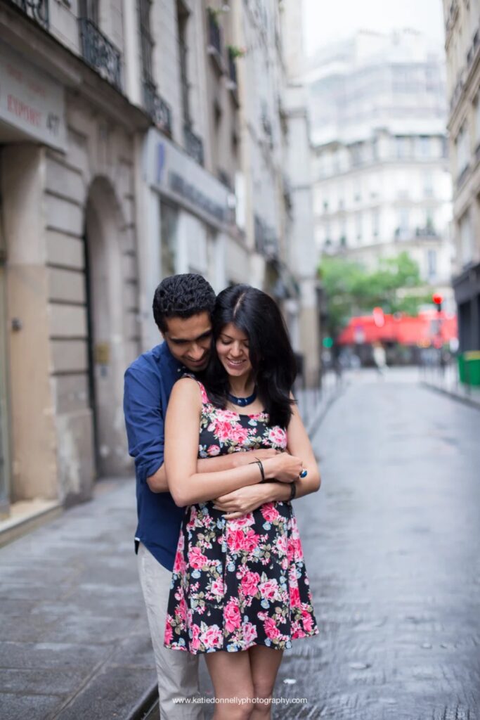 Expecting couple embracing on a rainy street in the Marais, Paris