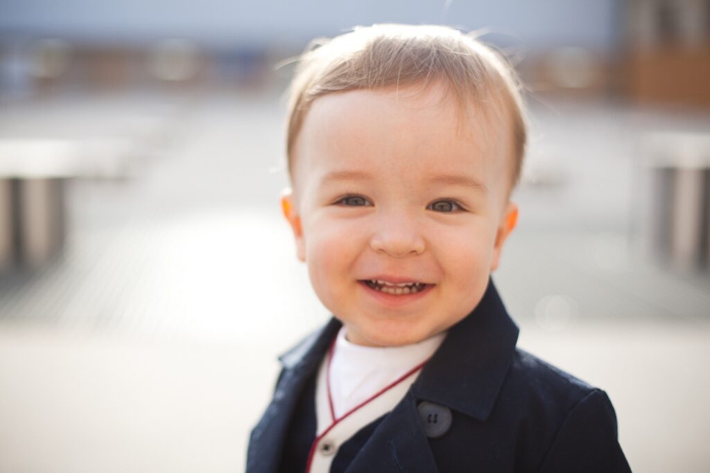 Close-up of a smiling toddler boy in a navy jacket at the Palais Royal in Paris