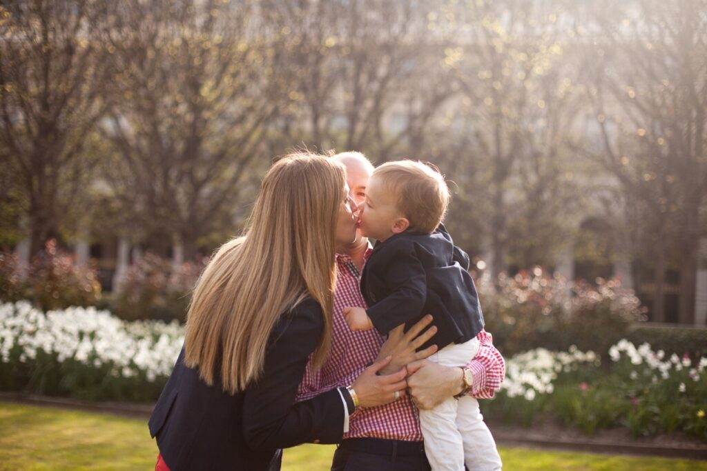 Mom kissing her toddler son in the gardens of the Palais Royal