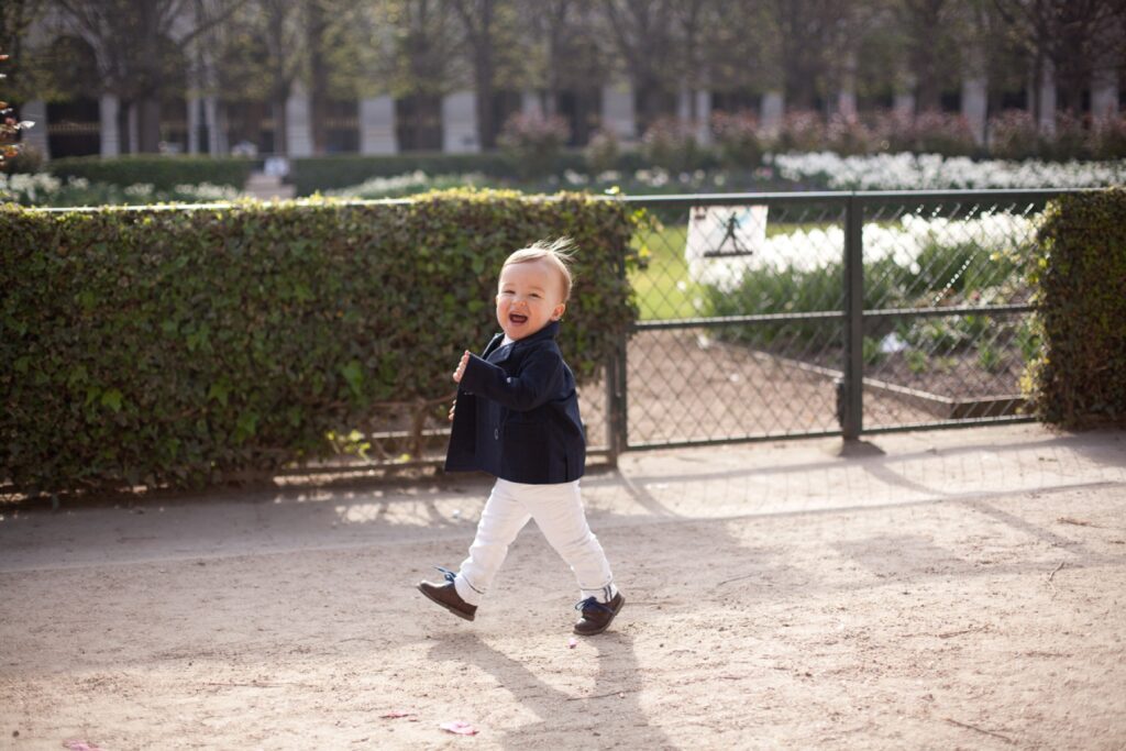 Toddler boy walking along a garden path at the Palais Royal