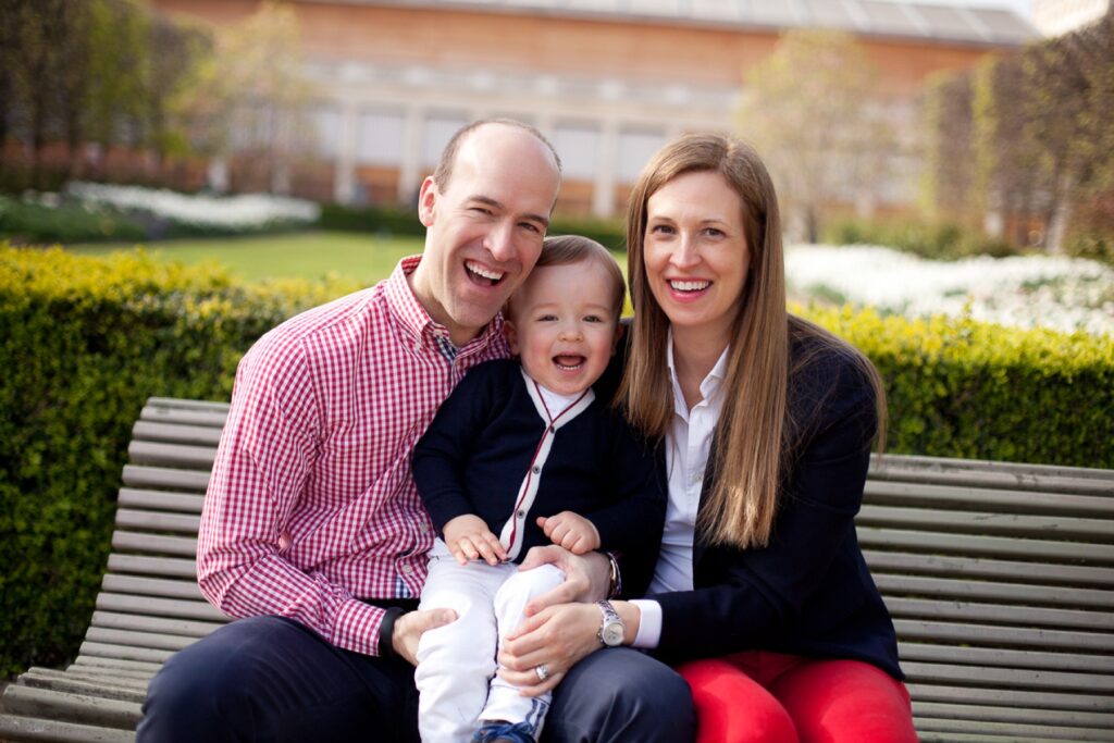 Family of three sitting together on a bench in the Palais Royal gardens
