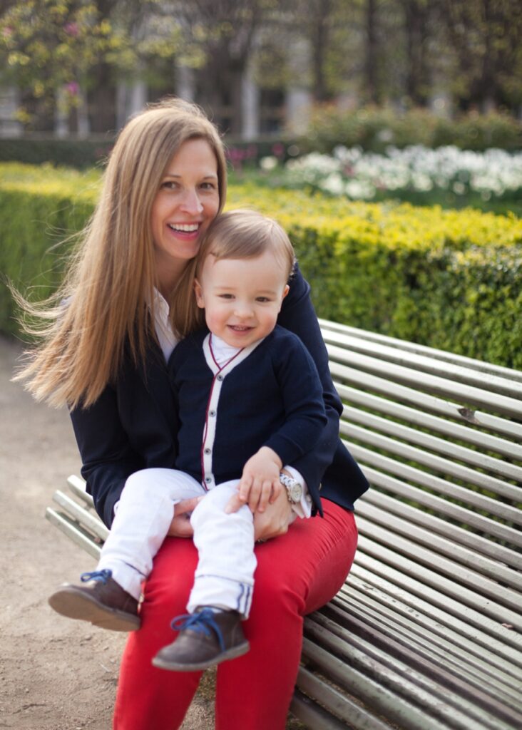 Mom sitting on a bench with her toddler son on her lap in the Palais Royal gardens