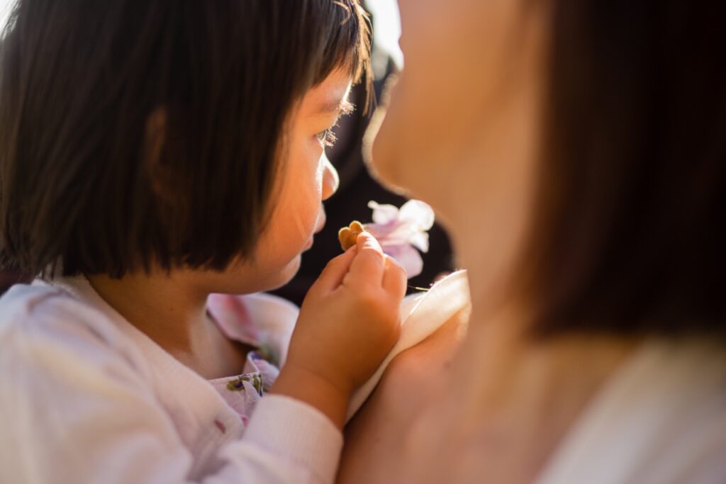 Close-up of a toddler girl smelling a flower held by her mother during a family photoshoot in Paris